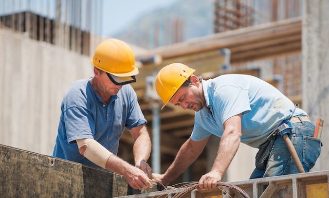 Authentic construction workers collaborating in the installation of cement formwork frames