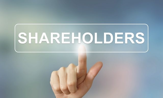 business hand pushing shareholders button on blurred background