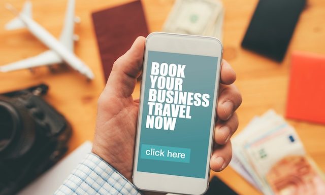 Book your business travel now online mobile app. Man holding smartphone with mock up application screen related to holiday vacation journey trip