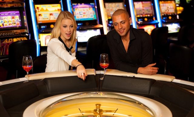 Young couple playing roulette in casino betting and winning