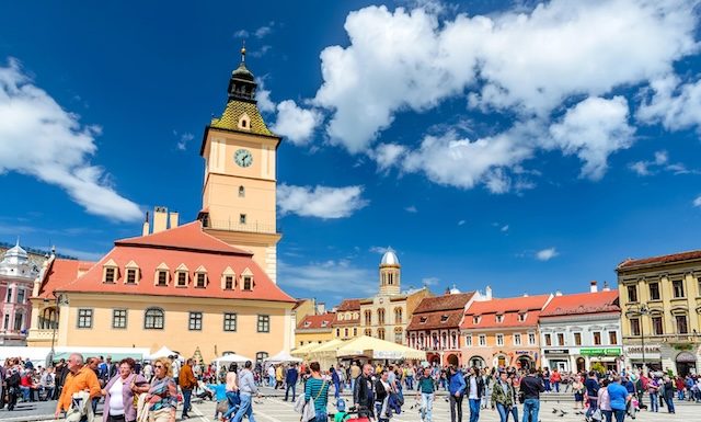 BRASOV, ROMANIA - 27 APRIL 2014: Scenery with tourists walking in Main Square, landmark with Council House in medieval center of Brasov, Transylvania, Romania.