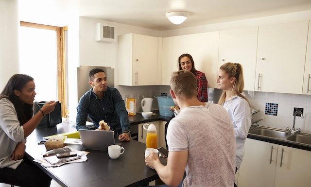 Students Relaxing In Kitchen Of Shared Accommodation