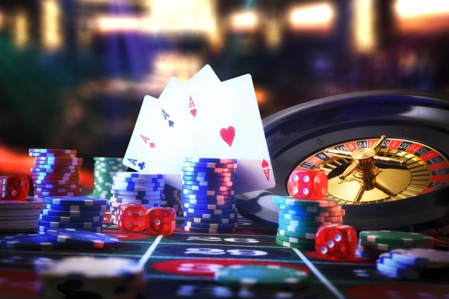 Detail of casino gaming table with game mat with stacks of betting chips on numbers and roulette, cards and dice with dark background of gaming room with lights. Front view.