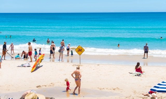 Byron Bay, NSW, Australia- January 3, 2018: People enjoying the sunny weather on the beach at Byron Bay, a popular destination with beaches and coastal trails on the North Coast of NSW, Australia.
