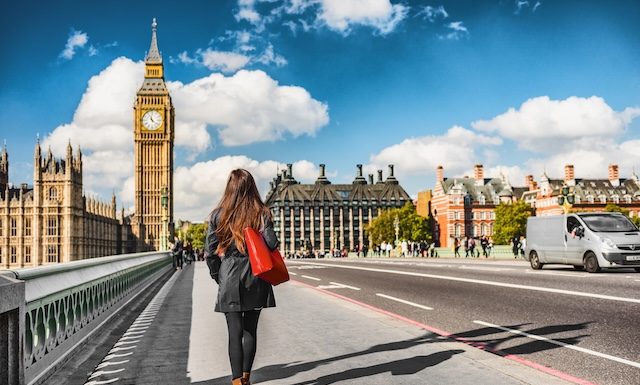 London city urban lifestyle tourist woman walking. Businesswoman commuting going to work on Westminster bridge street early morning. Europe travel destination, England, Great Britain, UK.
