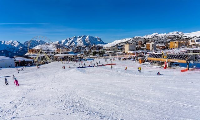 Alpe D'Huez, FRANCE - 01.01.2022: Famous ski resort in French Alps, France, Europe. Skiers skiing on the mountain, ski lift, family sports weekend, holidays in the snow mountains concept. Winter times