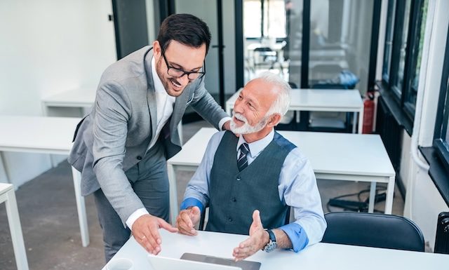 Senior boss happy for good online work result of young male businessman.