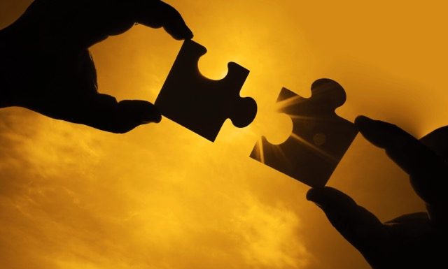 two hands trying to connect couple puzzle piece with sunset background. Jigsaw alone wooden puzzle against sun rays. one part of whole. symbol of association and connection. business strategy.