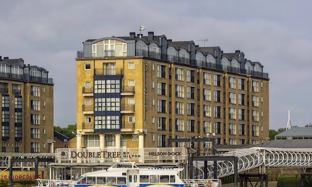 LONDON, UK - JULY 04, 2018: Thames Clipper river bus in front of DoubleTree by Hilton Hotel on Docklands Riverside @ credit Depositphotos.com