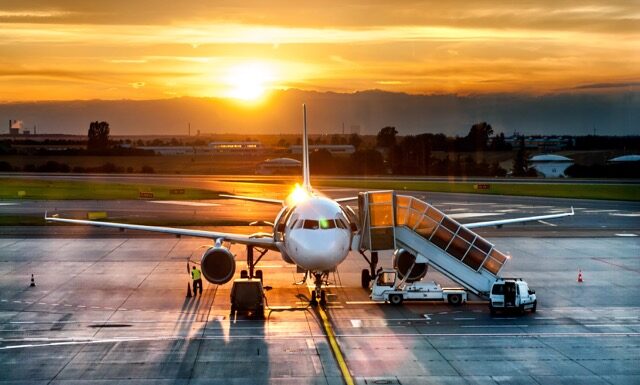 Airplane near the terminal in an airport at the sunset @ credit Depositphotos