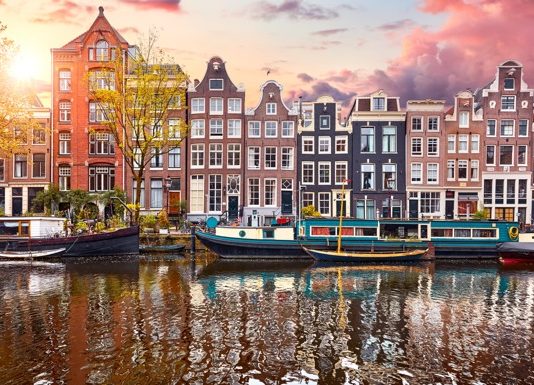 Pays-Bas | Le singapourien First Sponsor Group acquiert 33 % du Crowne Plaza Amsterdam South pour 58,1 millions d’euros Amsterdam, Netherlands. Panorama of famous dancing houses on river Amstel, water channels with house boats. Popular landmark and travel destination in old european city. Evening sunset landscape.