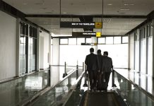 USA | Le voyage d’affaires aux États-Unis génère 623 milliards $ de PIB en 2024 businessmen walking on an airport moving walkway, discussing strategy during a business trip. Professional corporate travel and partnership concept