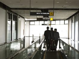 USA | Le voyage d’affaires aux États-Unis génère 623 milliards $ de PIB en 2024 businessmen walking on an airport moving walkway, discussing strategy during a business trip. Professional corporate travel and partnership concept