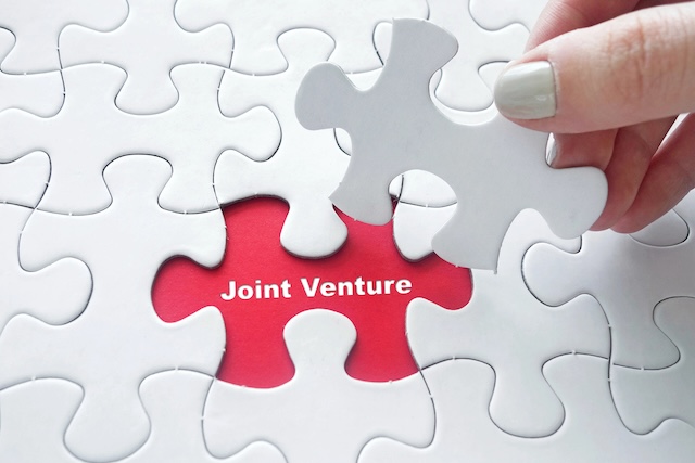 Corée du Sud | Shinsegae et OKO Group s’associent pour un fonds de 500 millions de dollars dédié à Aman Close up of girl's hand placing the last jigsaw puzzle piece with Joint Venture
