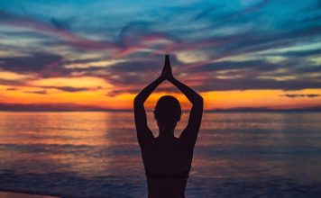 Young healthy woman practicing yoga on the beach at sunrise, benefits of natural environments for physical.