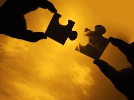 two hands trying to connect couple puzzle piece with sunset background. Jigsaw alone wooden puzzle against sun rays. one part of whole. symbol of association and connection. business strategy.