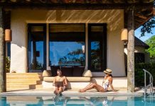Stratégie | Wyndham Rewards s’ouvre aux locations de vacances avec près de 800 villas et résidences Men working at a laptop a digital nomad working at a swimming pool during a vacation on a tropical island. man and woman in the infinity pool during sunset. luxury vacation in a luxury pool villa